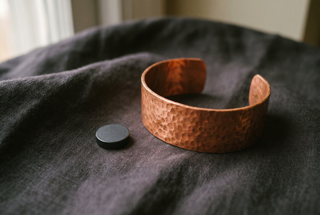 A solid copper bracelet with the magnet lying beside it, not sticking