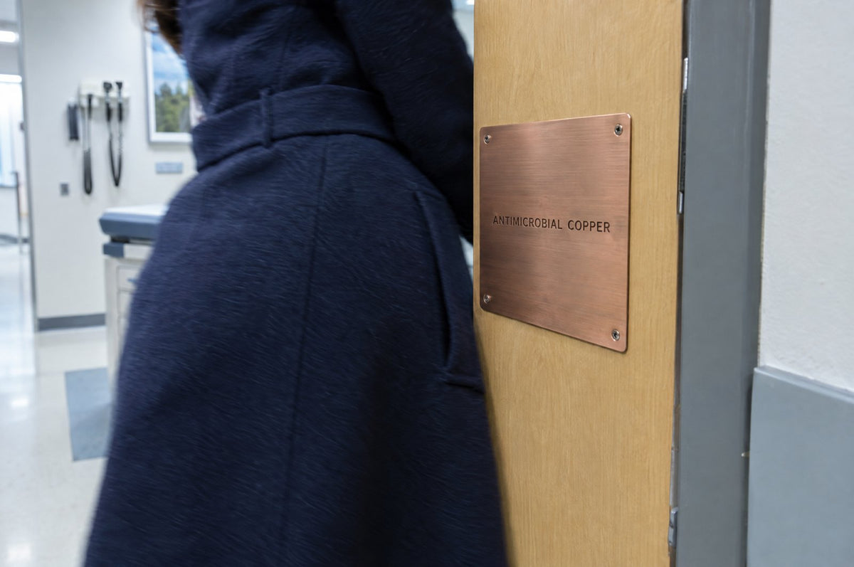 Antimicrobial copper push plate on an exam-room door