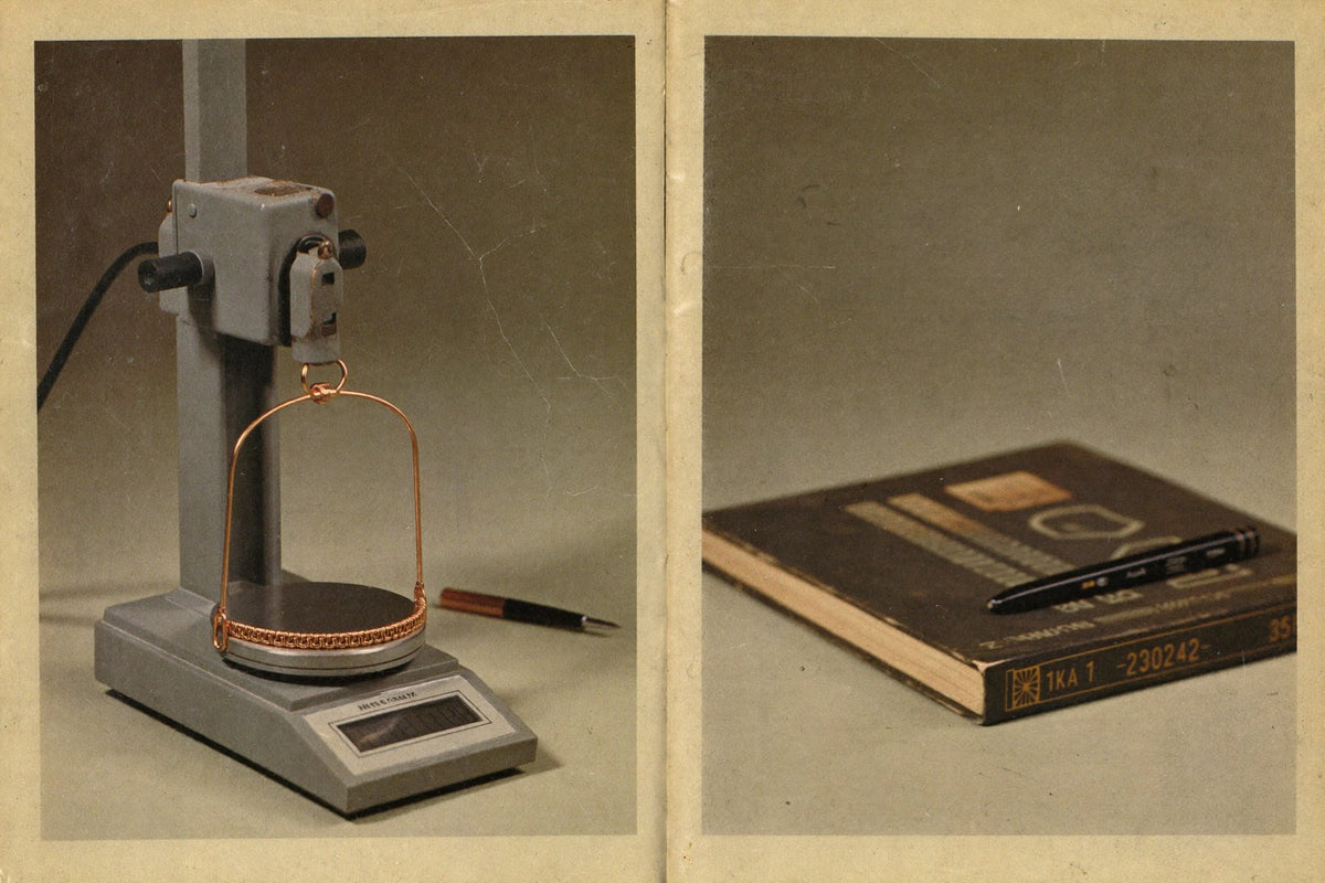 A photocopied journal page, yellowed at the edges, on a kitchen table under a reading lamp at night. Beside it a small d